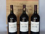 trois bouteilles de vin rouge sont posées devant une caisse en bois