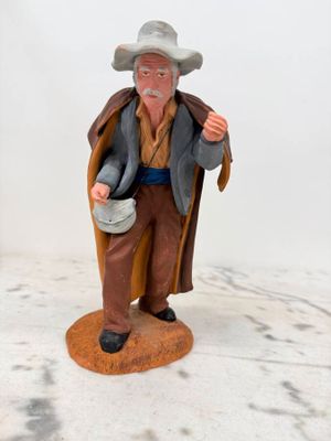 figurine représentant un vieil homme coiffé d'un chapeau et portant un gilet, tenant un seau