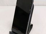 a black cell phone sitting on a stand on a white surface