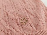a close up of a pink sweater with a gold ring on it