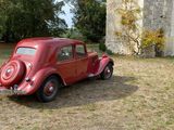 an old red car parked in front of a castle