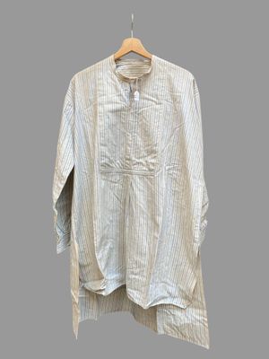 une chemise blanche suspendue à un cintre en bois devant un mur gris