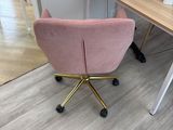 a pink chair that is sitting in front of a desk