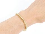 the woman is wearing a bracelet with gold beads on her arm
