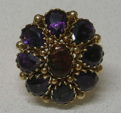 un gros plan d'une bague violette et dorée posée sur une surface blanche