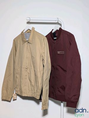 two jackets hanging on a clothes rack in a white room