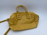 a yellow handbag with a strap on it sitting on a white surface