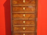an antique chest of drawers against a red wall