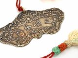 a silver pendant with a tassel on a red string