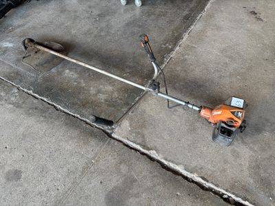 une petite tondeuse à gazon sur le trottoir, à côté d'une voiture