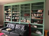 un canapé en cuir noir placé devant une bibliothèque verte