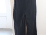 un pantalon noir sur un mannequin se tient devant une porte blanche