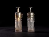 pair of clear glass bottles with gold caps on a black surface