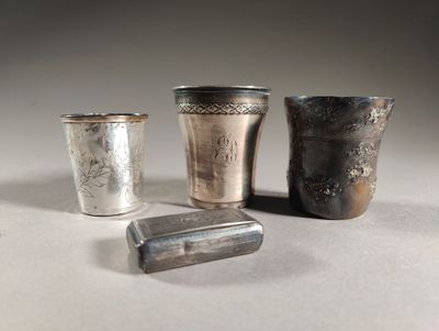 trois tasses en argent et un briquet sont posés sur une table