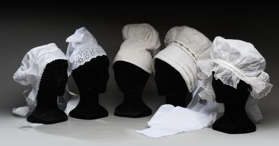 trois têtes de mannequins coiffées de chapeaux et drapées de tissus blancs