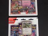 deux paquets de cartes à collectionner Pokémon posés sur une surface noire