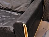 a black leather couch with a wooden frame on the floor