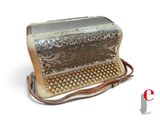 an old silver accordion sitting on top of a white surface
