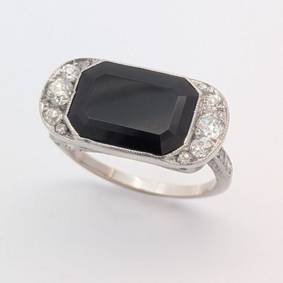 une image représentant une bague en pierre noire et diamant sur fond blanc
