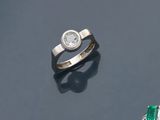 un gros plan d'une bague sertie d'un diamant et d'une émeraude sur une surface noire