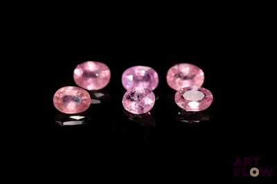 three pink sapphires on a black surface