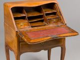 an old wooden desk with a red leather top and drawers
