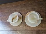 two cups and saucers sitting on a wooden table