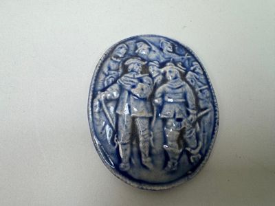 une petite assiette bleue et blanche sur laquelle est représenté un groupe de personnes