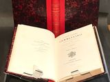 un livre ouvert posé sur une table, à côté de deux livres rouges