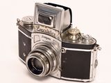 a silver and black camera sitting on a white surface