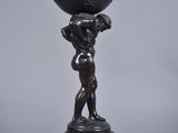 bronze statue of a boy holding a globe on his head