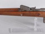 an old wooden rifle mounted on a clear stand on a white surface