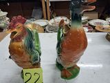 deux figurines de coq en céramique posées sur une table dans une boutique