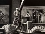 photographie en noir et blanc d'un homme debout sur un camion équipé d'une grue