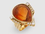une image représentant une bague ornée d'une pierre orange entourée de diamants