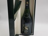 une boîte ouverte contenant une bouteille de champagne, posée sur une surface blanche