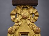 a gold clock with a wooden face on a stand
