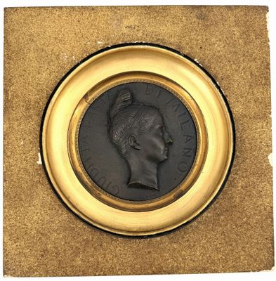 an old coin with a man ' s head on it in a gold frame