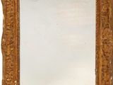 une image représentant un miroir à cadre doré posé sur un mur blanc