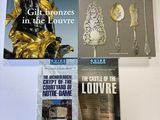 trois livres posés sur une table blanche, avec une statue dorée en arrière-plan
