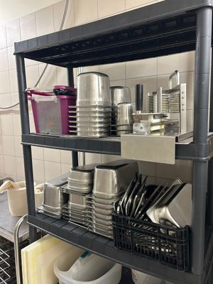 une étagère noire sur laquelle sont posés des casseroles et des poêles