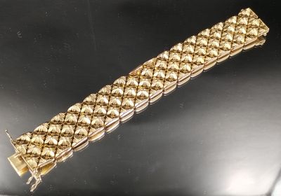 gros plan d'un bracelet en or sur une surface noire