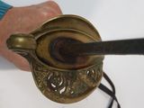 a person holding a metal spoon with a black handle