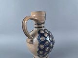 a small blue and white vase with a brown handle