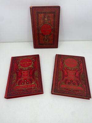 trois livres rouges posés les uns à côté des autres sur une table
