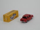 a red toy car next to a yellow box on a white surface