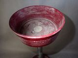 a red bowl sitting on top of a metal stand