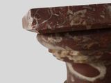 a close up of a marble pedestal with a bird perched on top of it