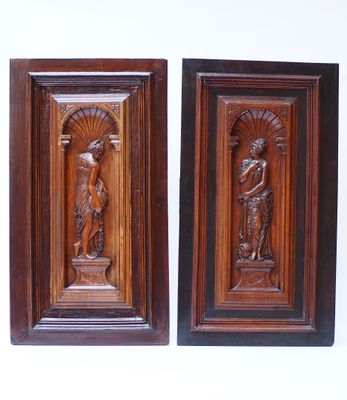 pair of carved wood plaques depicting a woman and a man