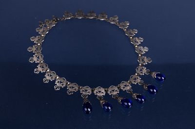 un gros plan d'un collier posé sur une table, sur fond bleu